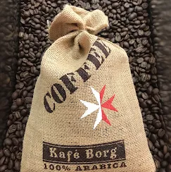 A burlap bag of Kafé Borg 100% Arabica coffee resting on roasted beans